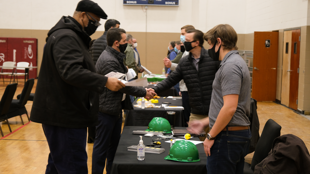 Several people having conversations, exchanging materials, and shaking hands