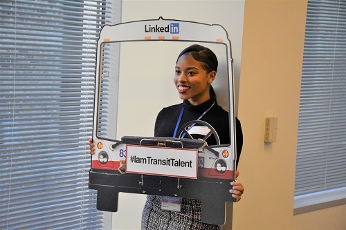 An intern posing for a picture holding a bus prop