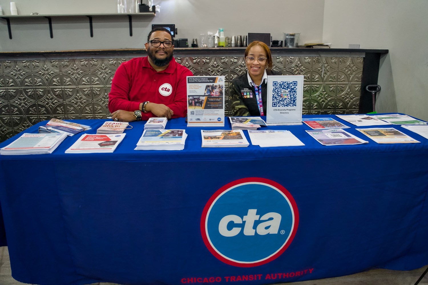 Two CTA employees sitting at a table with informational literature, ready to answer questions.