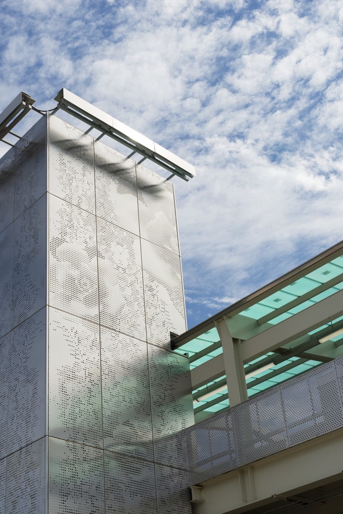 Close-up view of perforated steel wrap on elevator towers featuring a floral pattern