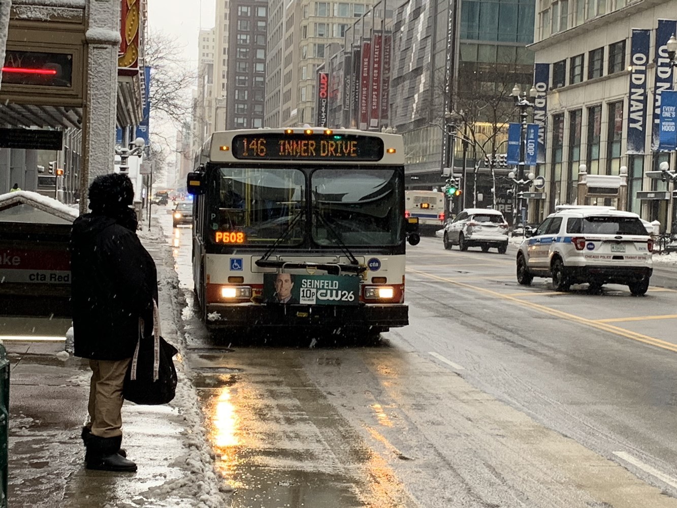 Customer at a bus stop cleared of snow outside the State/Lake Red Line subway entrance.