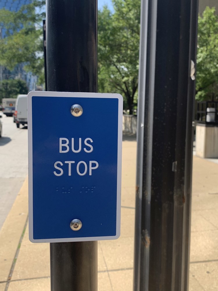 Close-up view of a tactile bus stop sign being installed across 12 bus routes in 2022 as part of a pilot.