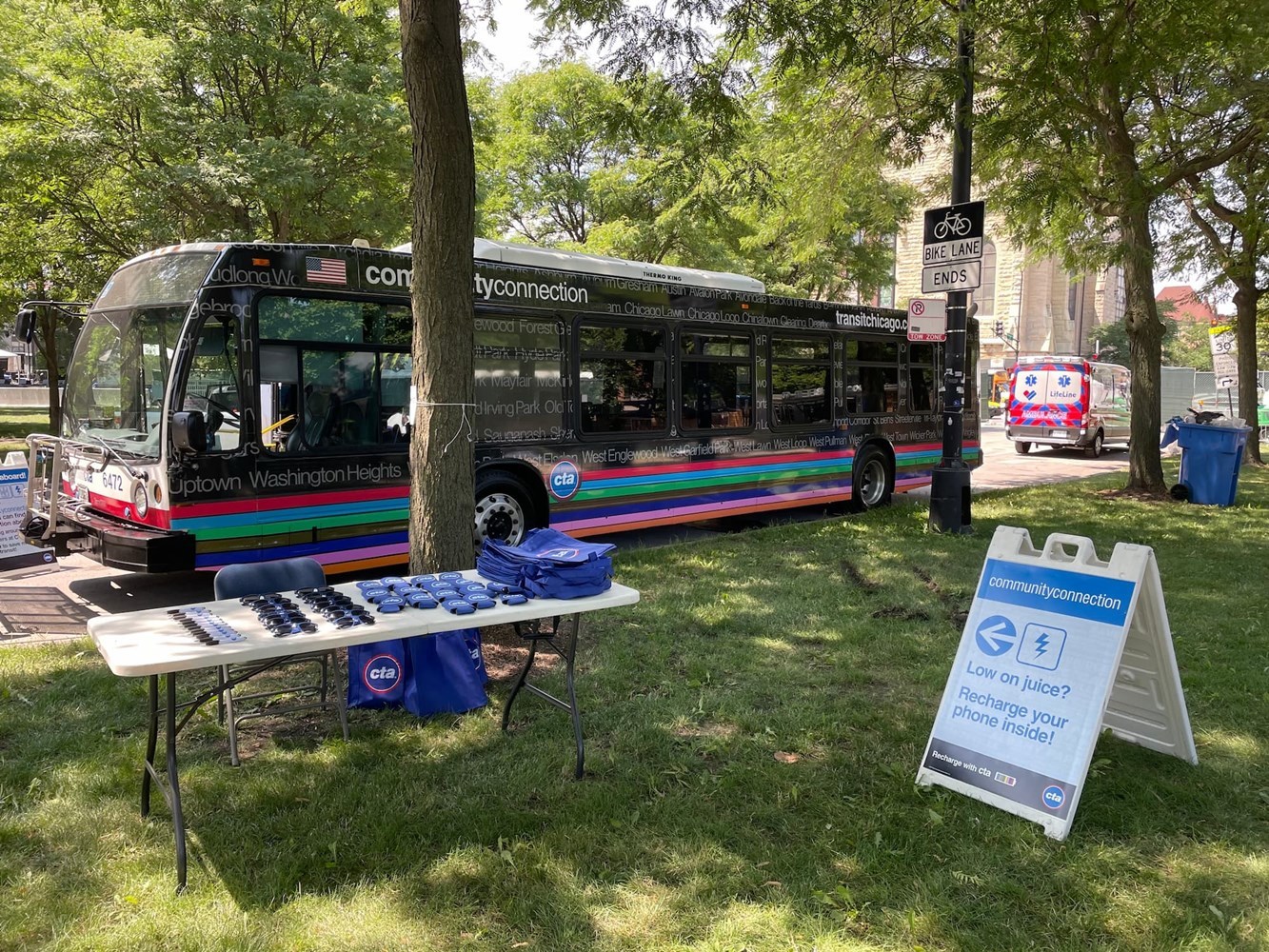 Community Connection bus parked in the shade with a sign saying: Low on juice? Recharge your phone inside!