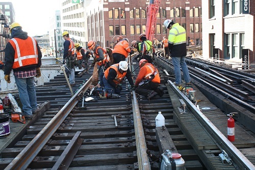 Infrastructure team in orange vests working on L tracks