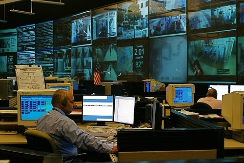 Several people at computers with a giant video wall