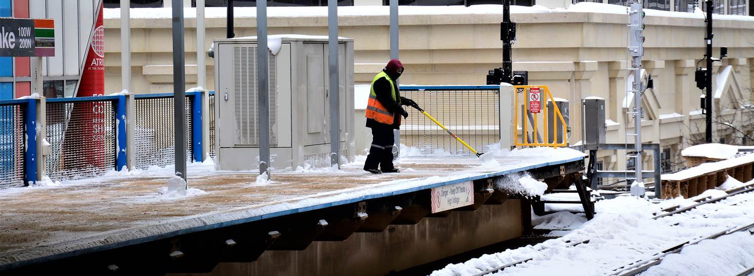CTA worker clearing snow off of the Clark/Lake platform