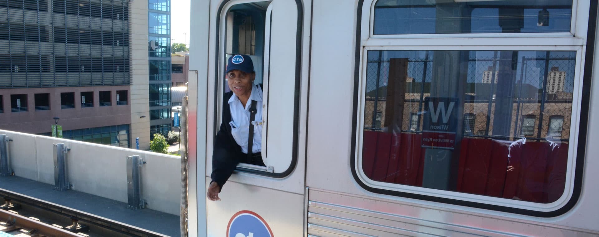 Rail operator waving from the cab of a train.
