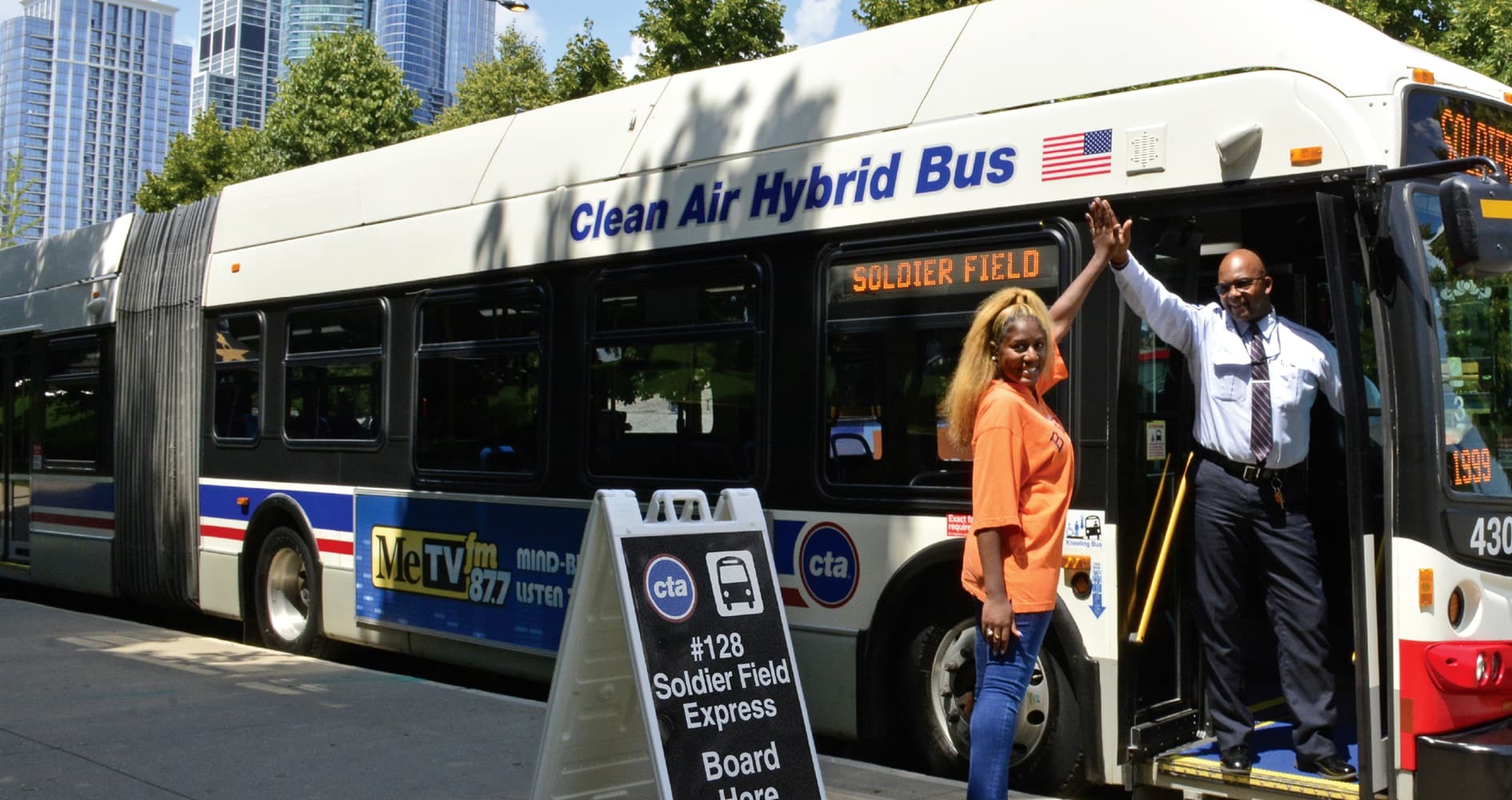 A rider high fives a bus operator who is standing in the door of a bus.
