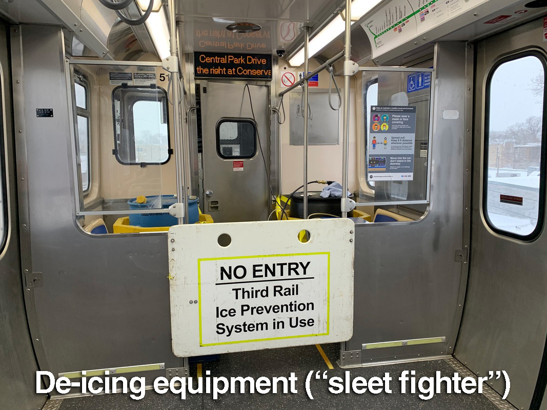 Barrel and machinery in a train car with a sign reading no entry, third rail ice prevention system in use